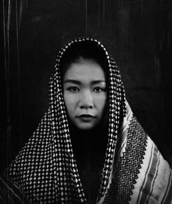 Close-up portrait of young woman standing against gray background