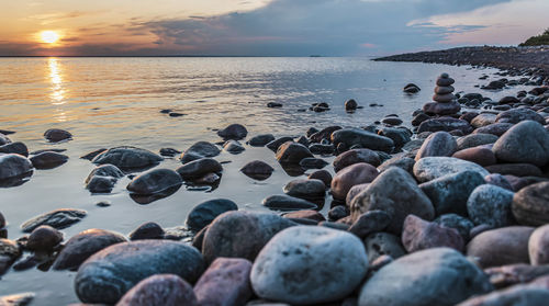 Rocks at beach against sky during sunset