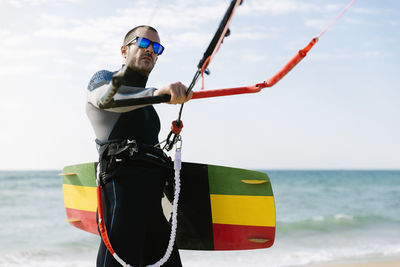 Man holding umbrella on land against sea