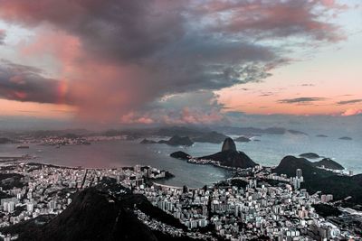 Aerial view of townscape by sea against sky during sunset