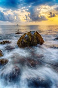 Scenic view of rocks in sea against sky during sunset