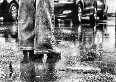 Low section of man standing on puddle during rainy season