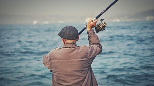 Rear view of man fishing in sea