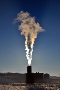 Smoke emitting from chimney against sky