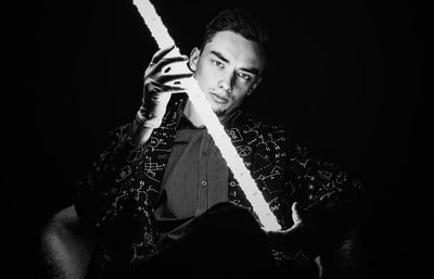 Portrait of mid adult man sitting against black background