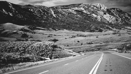 Road by mountains against sky