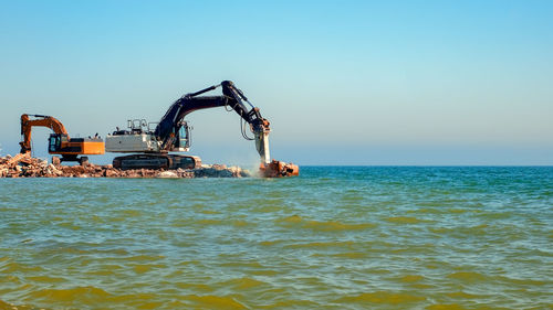 Excavators crashing concrete into the sea