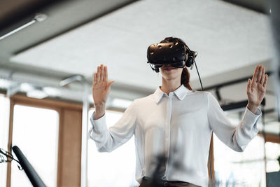 Female entrepreneur doing stop gesture while using virtual reality simulator at office