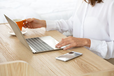 Midsection of woman using laptop on table