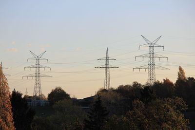 Low angle view of electricity pylon against sky during sunset