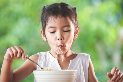 Cute girl eating noodles in public park