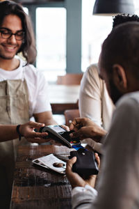 Man doing credit card payment to waiter at table in restaurant