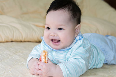 Cute baby boy eating while lying on bed