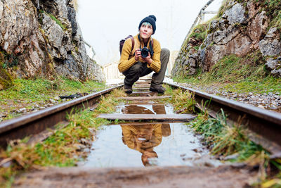 Portrait of young woman sitting on railroad track