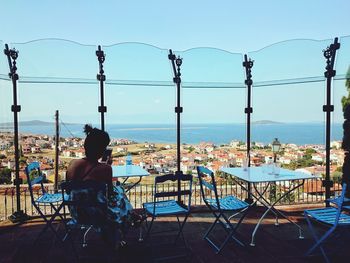 Man sitting on table by sea against clear sky