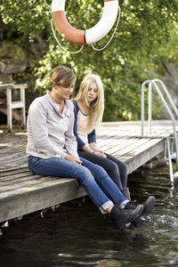 Mother and daughter sitting on pier