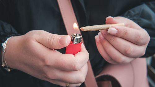 Close-up of woman hand igniting marijuana with cigarette lighter