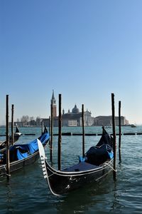 Boats moored in canal against clear sky