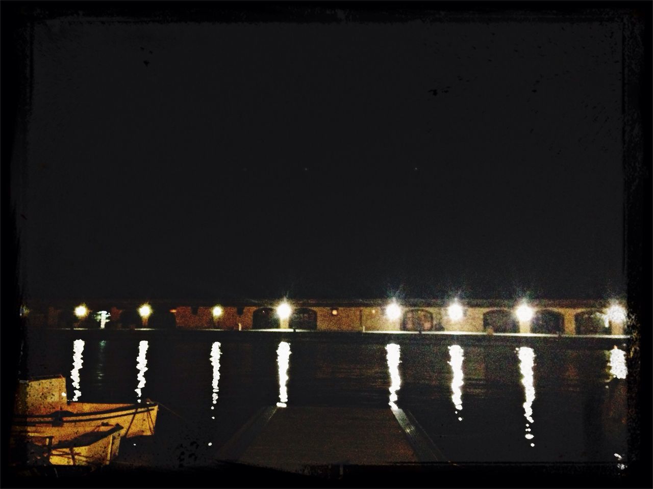 night, illuminated, water, reflection, copy space, clear sky, sea, lighting equipment, river, dark, waterfront, pier, no people, outdoors, street light, lake, built structure, light - natural phenomenon, in a row, sky