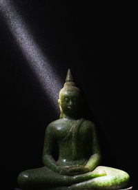 Statue of buddha against black background