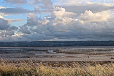 Scenic view of beach against cloudy sky