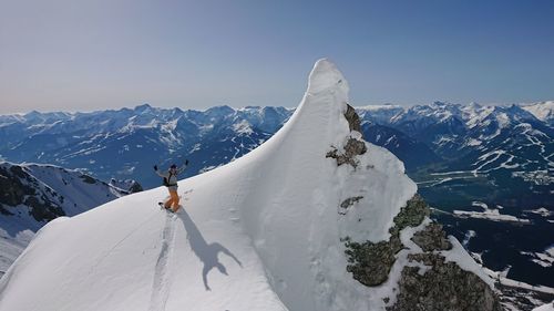 Man snowboarding on mountain against sky