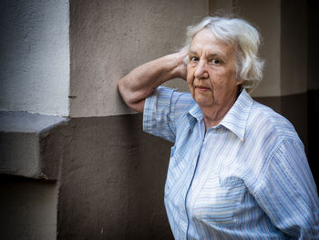 Mid adult woman looking away against wall