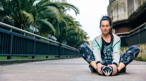 Woman runner with closed eyes relaxing sitting on the floor after training