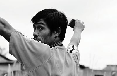 Portrait of man with arms outstretched against clear sky