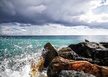 Sea waves splashing on rocks against sky