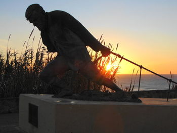 Man by sea against clear sky during sunset