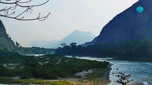 Scenic view of river by mountains against sky