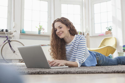 Woman at home lying on floor using laptop