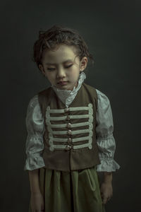 Cute boy standing against black background