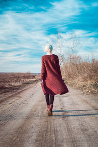 Rear view of woman walking on road against sky