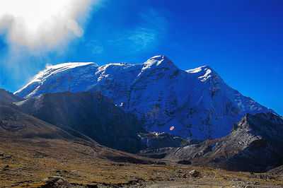 Scenic view of snowcapped mountains against blue sky