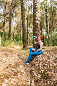 Side view of athlete drinking water in forest