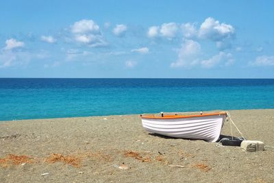 Deck chairs on beach against blue sky