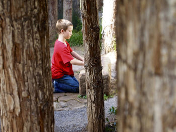 Side view of boy kneeling on field at santa barbara botanic garden