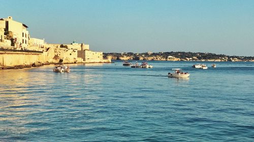 Buildings by sea against clear sky