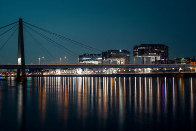 Illuminated bridge over river against sky at night