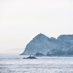 Scenic view of sea and mountains against clear sky