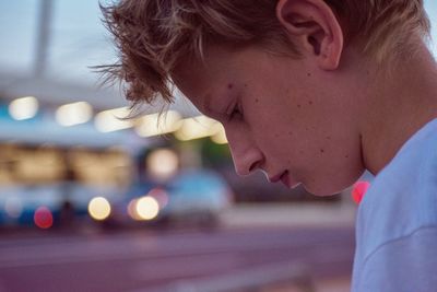 Close-up of boy looking down in city