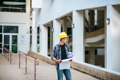 Man holding umbrella standing outside building