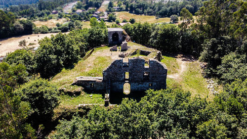 Old ruin amidst trees and plants on field