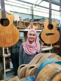 Smiling young woman standing by guitars at store