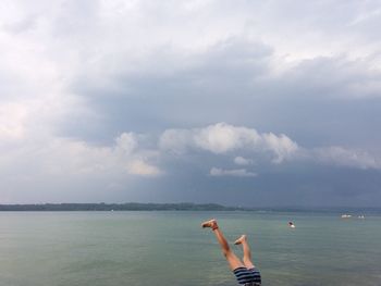 Low section of child in sea against sky