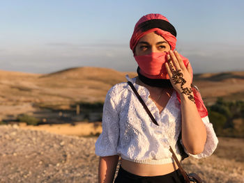 Young woman wearing headscarf standing on land against sky