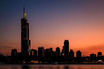 Illuminated buildings in city against sky during sunset