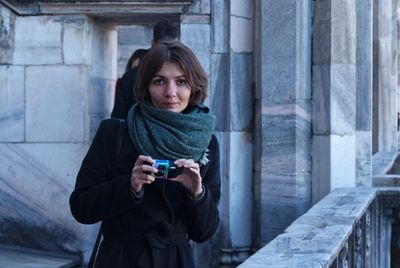 Portrait of young woman using phone while standing in snow